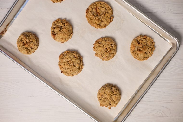 Scoops of oatmeal apple cinnamon cookie dough spaced on a parchment-lined baking sheet.