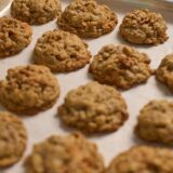 Freshly baked oatmeal apple cinnamon cookies on a parchment-lined tray.