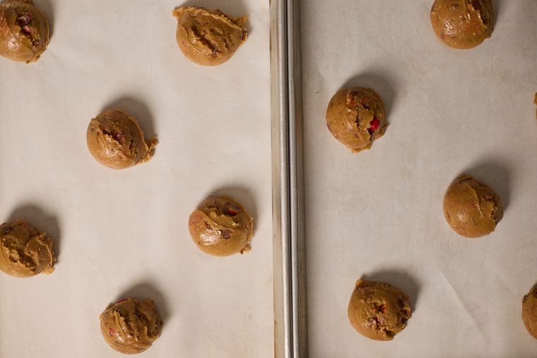 Scooped Cadbury egg cookie dough spaced on parchment-lined baking sheets.