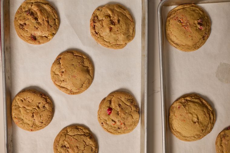 Freshly baked browned butter Cadbury egg cookies on parchment-lined trays.