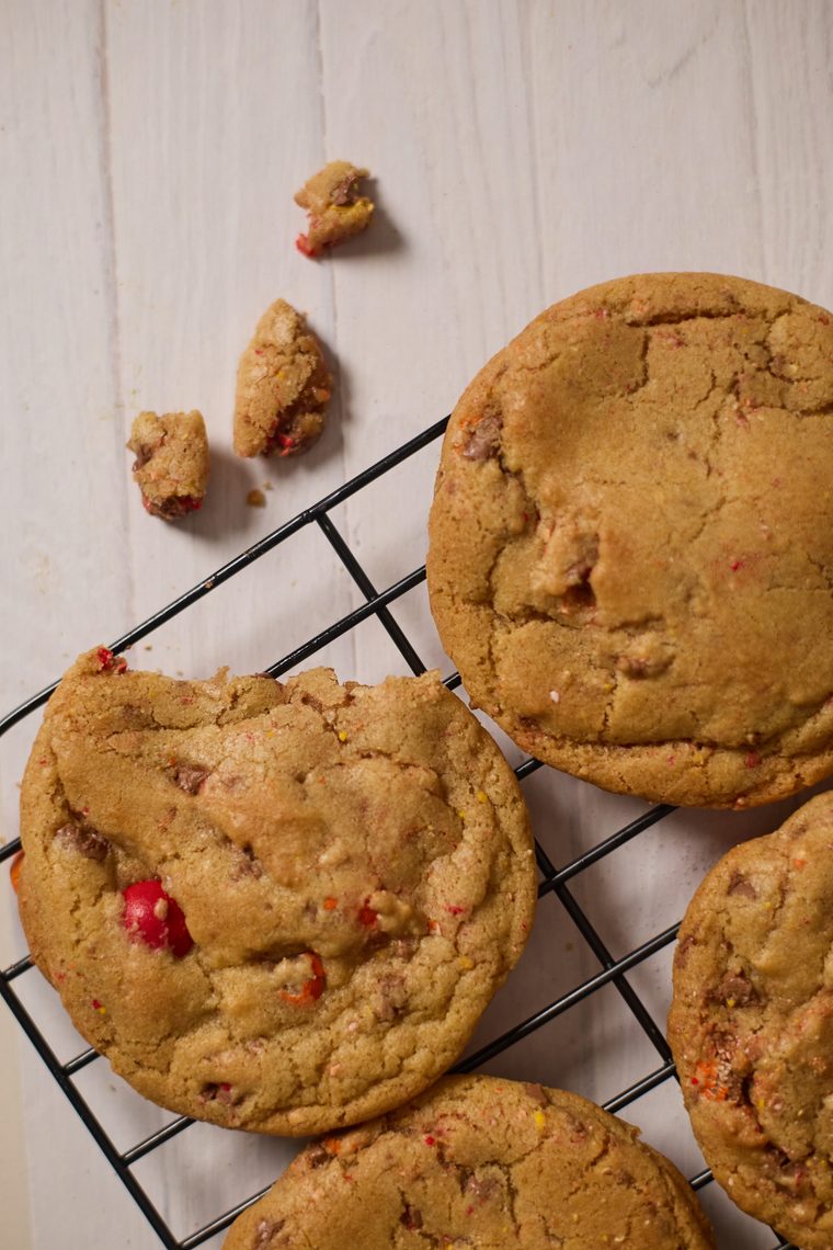 Close-up of browned butter cookies with colorful Cadbury egg pieces on a wire rack.