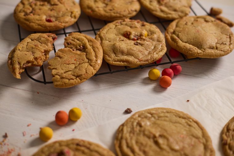 Browned butter Cadbury egg cookies and scattered chocolate eggs beside a cooling rack.