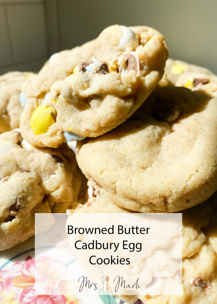 Chunky, gooey cookies loaded with Cadbury Egg bits pile up on a plate. Text says: Browned Butter Cadbury Egg Cookies Mrs Madi.