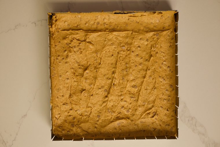 Pumpkin bar batter spread evenly in a parchment-lined square pan.