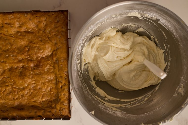 Baked pumpkin bars beside a bowl of cream cheese frosting.