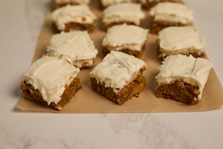 Frosted pumpkin bar squares arranged on parchment paper.