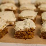 Pumpkin bars cut into squares and topped with thick cream cheese frosting.