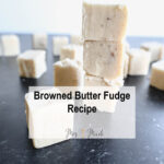 Piles of browned butter fudge mixed with luscious white chocolate are spread out on a dark background, with more yummy pieces scattered around. A text on top says, Browned Butter Fudge Recipe.