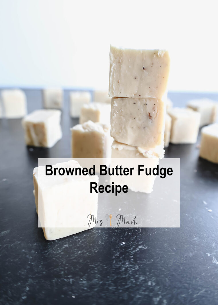 Piles of browned butter fudge mixed with luscious white chocolate are spread out on a dark background, with more yummy pieces scattered around. A text on top says, Browned Butter Fudge Recipe.
