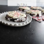 Check out these yummy chocolate cookies topped with white icing and candy cane bits, all served up on a cute scalloped plate. In the background, you can see more cookies just waiting to be eaten! Up above, theres a sign saying Chocolate Candy Cane Cookie Recipe from Mrs. Mad.