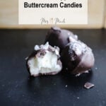 Check out these two chocolate-covered peppermint buttercream candies! Ones got a bite taken out, showing its yummy white filling. In the back, theres a wooden tray loaded with more goodies. A sign above says “Homemade Peppermint Buttercream Candies,” just begging you to give this tasty treat a try!.