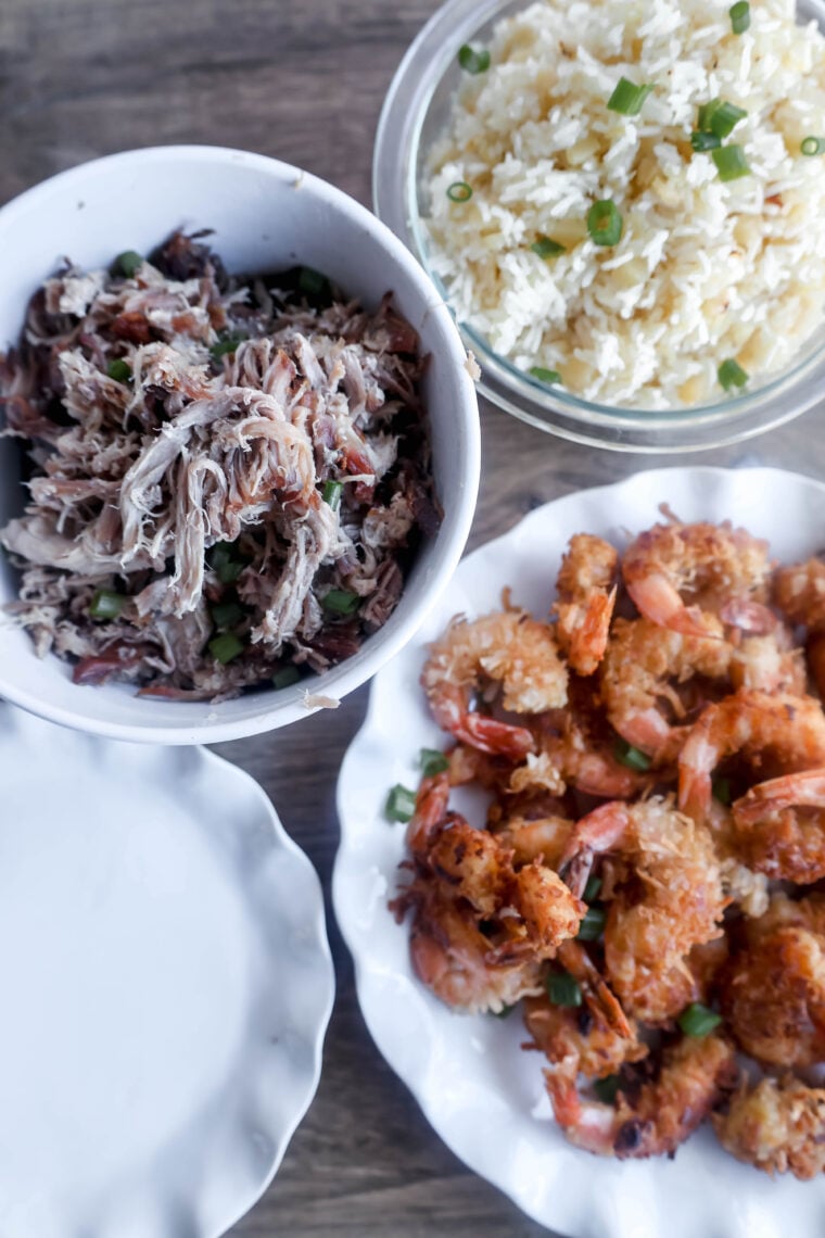 Theres a table with three dishes: a bowl of shredded meat sprinkled with green onions, some pineapple rice tossed with green onions, and a plate of crispy shrimp topped with—you guessed it—green onions. All this goodness is laid out on a wooden table.