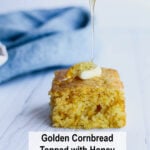 A slice of golden cornbread with melty butter and a sweet honey drizzle sits on a white plate. Text below: Homemade Cornbread with Honey Recipe.