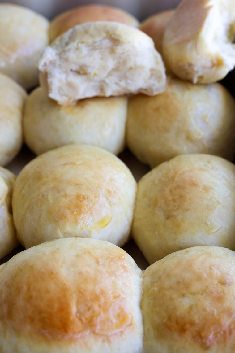 Check out these fresh, golden-brown dinner rolls! They’re super soft and shiny on top, and you can see how fluffy they are inside where one’s been pulled apart.
