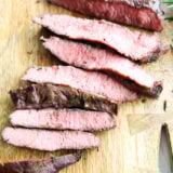 Juicy grilled steak, sliced up on a wooden board—perfectly pink inside with a tasty, seared crust.