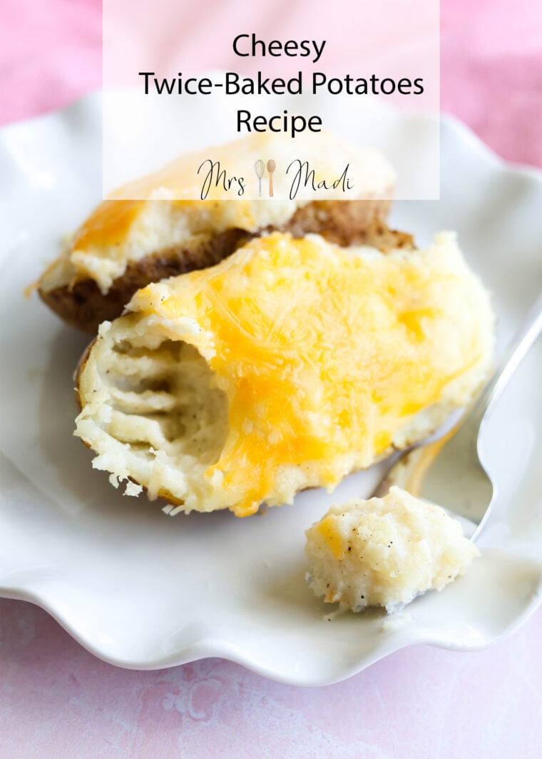 Cheesy twice-baked potatoes on a white plate, fork ready with a bite! Text says: Cheesy Twice-Baked Potatoes Recipe by Mrs Mad. If you love classic twice-baked potatoes, you’ll want to try this one!.