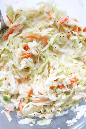 Here’s a close-up of creamy coleslaw, loaded with shredded cabbage, carrots, and poppy seeds all mixed in a light dressing—it’s a fresh spin on the classic!.