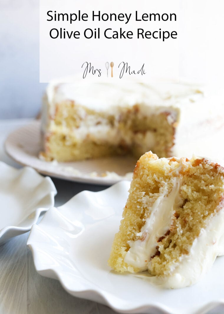A piece of honey lemon olive oil cake with creamy frosting is on a white plate, right in front of the whole cake. The text up top says: Simple Honey Lemon Olive Oil Cake Recipe.