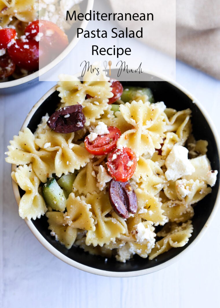 A bowl of Mediterranean pasta salad topped with farfalle, cherry tomatoes, cucumber, olives, and feta—yum! Text above says: Mediterranean Pasta Salad Recipe by Mrs. Madd. A classic favorite you’ll love!.
