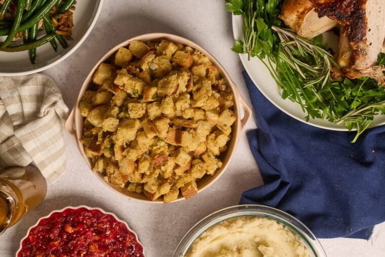 Oven-baked stuffing, green beans, mash, cranberries, gravy, and herby roast turkey on a light table—holiday vibes!.