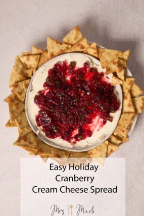 Cranberry cream cheese dip on a platter with herbs and crackers. Text: Easy Recipe&mdash;Holiday Cranberry Cream Cheese Spread.