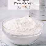 Glass bowl of flour on marble counter, with notes about bread vs all-purpose flour. Sifter and striped towel in the back.