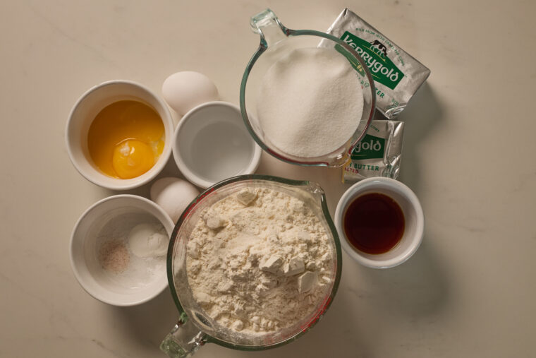 All the stuff you need for samoa sugar cookies&mdash;eggs, flour, sugar, butter, and more&mdash;spread out in bowls on the counter.