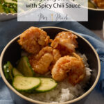 A bowl of rice topped with crispy bang bang shrimp, chili sauce, cucumber slices, and the text "Crispy Bang Bang Shrimp.