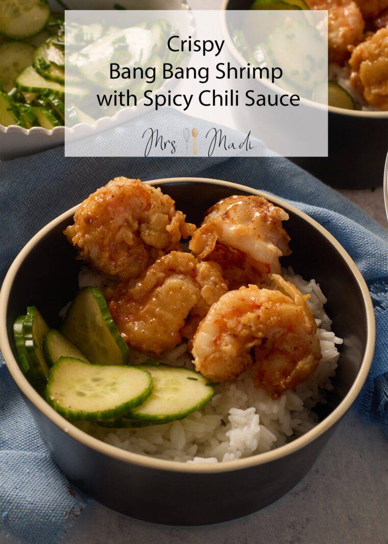 A bowl of rice topped with crispy bang bang shrimp, chili sauce, cucumber slices, and the text "Crispy Bang Bang Shrimp.