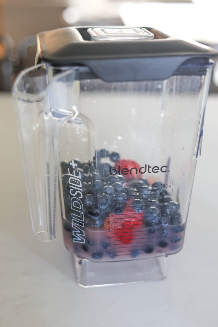 A Blendtec Wildside+ blender jar packed with blueberries and some strawberries, ready for tasty berry pops.