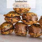 A pile of homemade chocolate chip cookie ice cream sandwiches sits on a pale pink surface, ready to be devoured.