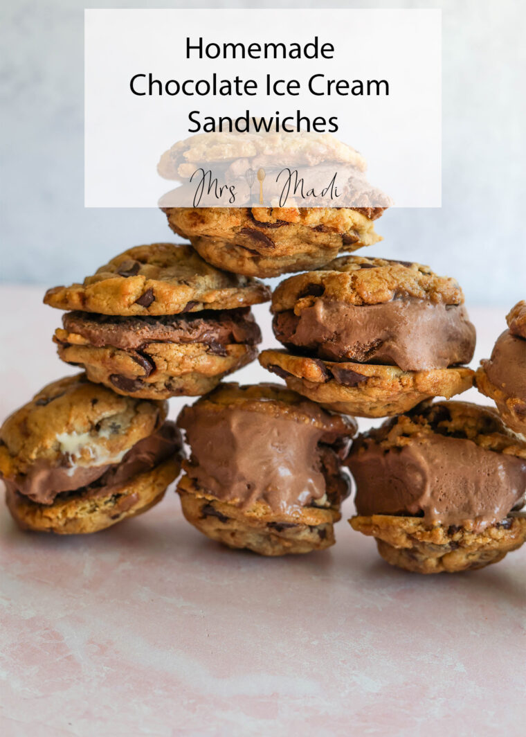 A pile of homemade chocolate chip cookie ice cream sandwiches sits on a pale pink surface, ready to be devoured.