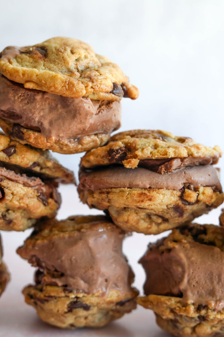 Stacks of homemade chocolate ice cream sandwiches with classic cookies and rich filling, set against a simple background.