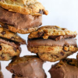 Stacks of homemade chocolate ice cream sandwiches with classic cookies and rich filling, set against a simple background.