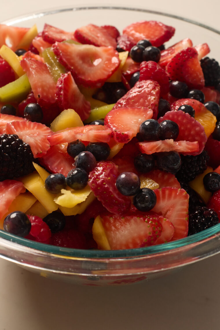 A glass bowl packed with fresh fruit salad&mdash;strawberries, blueberries, blackberries, raspberries, plus colorful chunks.