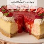A slice of creamy strawberry cheesecake loaded with sauce, white chocolate, whipped cream, and fresh strawberries on a plate.