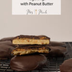 A bunch of chocolate-dipped shortbread cookies chill on a rack; one’s split open to show its peanut butter center.