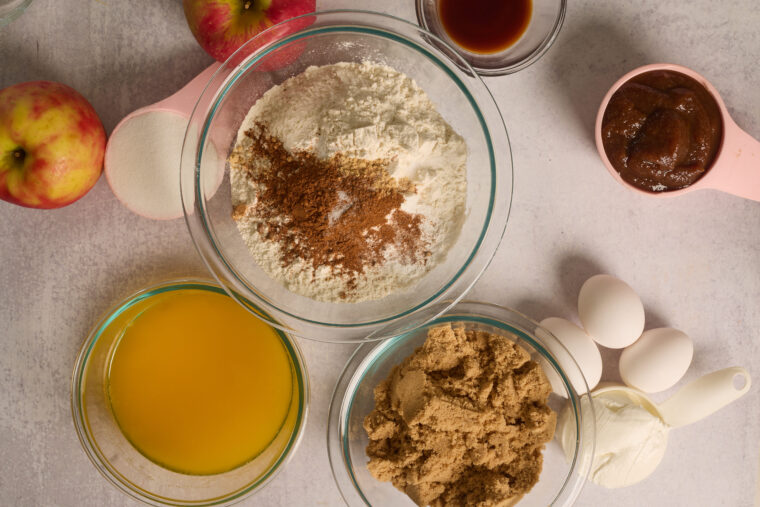 Flour, cinnamon, and other dry ingredients measured into a bowl for apple cake.