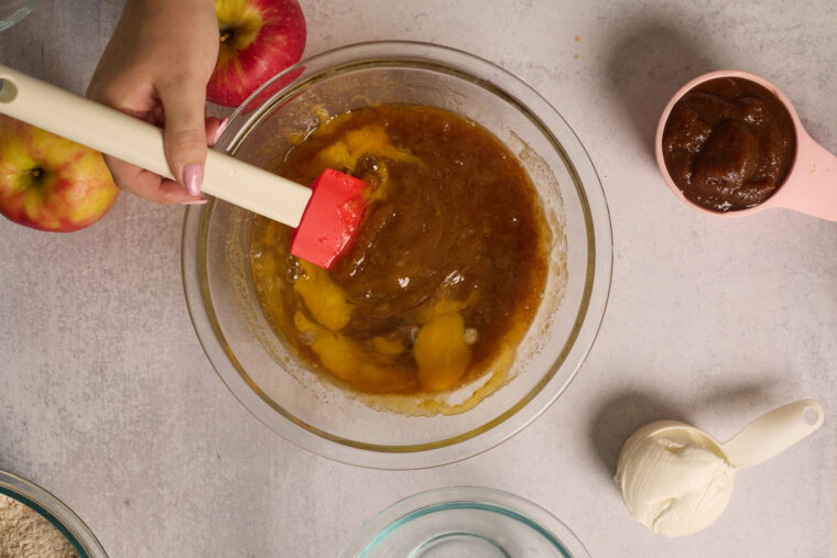 Eggs being stirred into the butter and sugar mixture for apple cake.