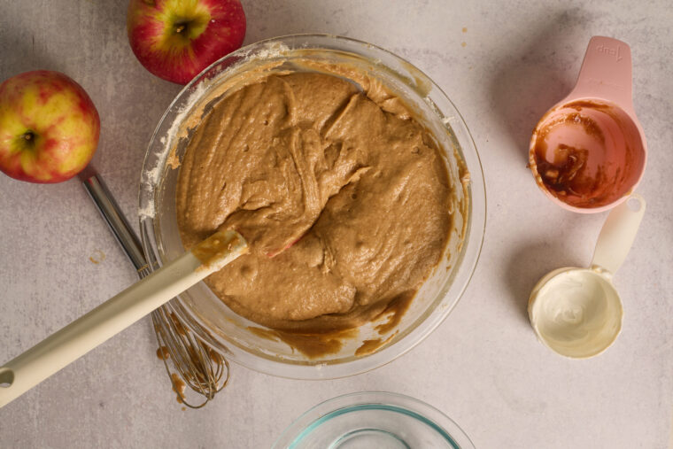 Spiced apple cake batter mixed until smooth in a glass bowl.