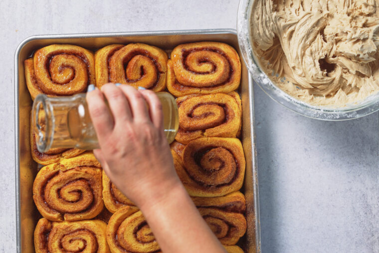 pouring maple syrup on freshly baked rolls