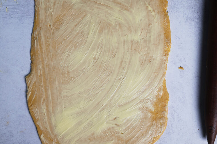 pumpkin cinnamon roll dough rolled out with butter on top